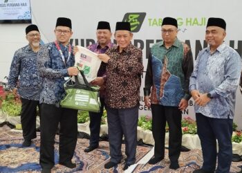 AMINUDDIN Harun (tiga dari kanan) menyampaikan kit haji kepada Setiausaha Majlis Agama Islam Negeri Sembilan (MAINS), Zainal Said sambil diperhatikan Mohamed Heikal pada Majlis Perasmian Penutup Kursus Perdana Haji Peringkat Negeri Sembilan di Seremban hari ini.-UTUSAN/NAZARUDIN SHAHARI