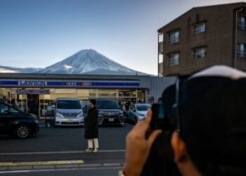 SEORANG pelancong bergambar di hadapan kedai serbaneka dengan latar belakang Gunung Fuji, di bandar Fujikawaguchiko, wilayah Yamanashi pada 1 Jan lalu. -AFP