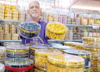 KASSIM Osman menunjukkan biskut raya yang dijual di kedainya di Tapah, Perak. - UTUSAN/MEGAT LUTFI MEGAT RAHIM