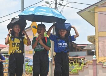 BEBERAPA murid menutup kepala menggunakan beg dan payung berikutan cuaca panas ketika pulang dari Sekolah Kebangsaan Padang Mengkuang, Marang, Terengganu. – UTUSAN/PUQTRA HAIRRY ROSLI