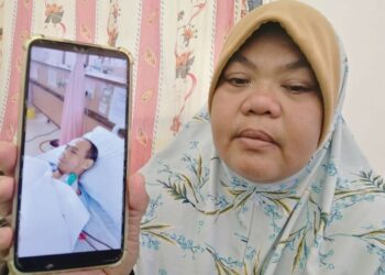 NORRISHAM Samsuddin menunjukkan gambar Mohd. Azmi Yusoh yang menerima rawatan di HSNZ ketika ditemui di rumahnya di Kampung Nibong, Hulu Terengganu. - UTUSAN/NOOR HAYATI MAMAT