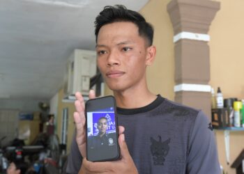 AHMAD Azza Fitri Azhar menunjukkan gambar Ahmad Azza Fahmi Azhar yang maut semasa serangan Balai Polis Ulu Tiram ketika ditemui di kediaman keluarganya di Kampung Poh, Bidor hari. UTUSAN/ZULFACHRI ZULKIFLI