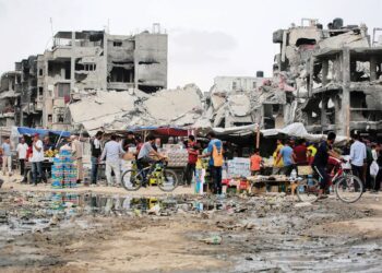 RAKYAT Palestin membeli barangan keperluan di pasar sementara berhampiran bangunan yang rosak teruk di Khan Younis, Selatan Gaza.- AFP