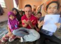 RAJA Amirul Mukmin Raja Safari (kanan) menunjukkan slip keputusan SPM bersama keluarganya di Kampung Gong Manak, Pasir Puteh semalam. – UTUSAN/TOREK SULONG