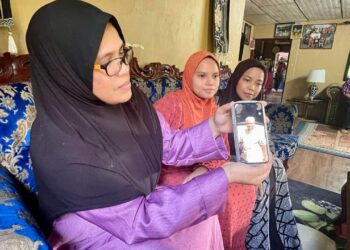 Noor Shakila (kiri) di samping adiknya, Noor Ikma Juana, 43, dan Nur Athirah, 28, menunjukkan gambar Allahyarham Abnil Hajar Ismail ketika ditemui di Kampung Tanjong, Tunjang, Kubang Pasu.