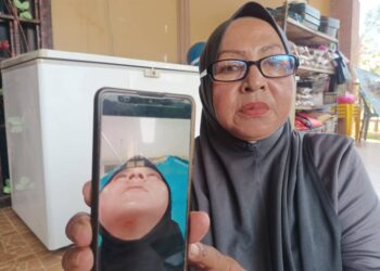 NARIZAH Nor menunjukkan gambar anaknya Siti Aishah yang mengalami kecederaan dalam kejadian bom di Narathiwat, Thailand semasa ditemui di Kampung Geting, Tumpat, Kelantan-UTUSAN/ROHANA MOHD. NAWI.