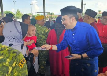 ASYRAF Wajdi  Dusuki  menyampaikan duit raya kepada kanak-kanak pada Majlis Rumah Terbuka Aidilfitri Daerah Kecil Pengkalan Hulu Parlimen Gerik hari ini. - UTUSAN