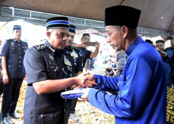 AZHAR Khaiden (kanan) menerima serahan Jalur Gemilang daripada Timbalan Ketua Polis Negara, Datuk Seri Ayob Khan Mydin Pitchay pada pengebumian jenazah anaknya, Ahmad Azza Fahmi Azhar di Bidor hari ini. - UTUSAN/ZULFACHRI ZULKIFLI