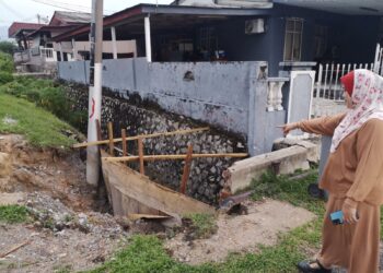 AYU Azura Ibrahim menunjukkan hakisan tanah berlaku berhampiran rumahnya di Jalan Kenanga 17, Taman Satria, Senawang, Seremban. – UTUSAN/NUR SHARIEZA ISMAIL