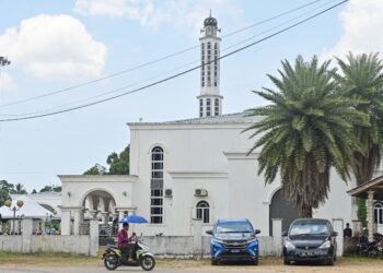 SEORANG penduduk menggunakan payung ketika hadir untuk menunaikan solat di Masjid Binjai Rendah, Marang.  - UTUSAN/PUQTRA HAIRRY ROSLI