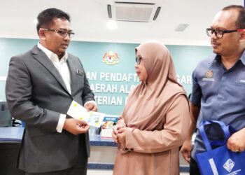 BADRUL HISHAM Alias (kiri) menyampaikan MyKad kepada seorang penerima pada Majlis Penamaan Semula Pejabat JPN Daerah Alor Gajah di Alor Gajah, Melaka. - UTUSAN/MUHAMMAD SHAHIZAM TAZALI