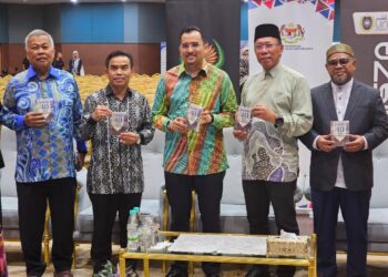 ASRAF Wajdi Dasuki (tengah) menunjukkan buku poket Hadis 40 Imam Al-Nawawi pada majlis pelancaran buku itu di UniSZA, Kuala Nerus, hari ini.