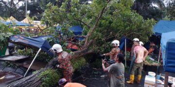 ANGGOTA bomba melakukan kerja-kerja mengalihkan pokok yang tumbang yang menghempap dua khemah peniaga di tapak pasar malam Taman Semarak, Nilai, Seremban petang tadi.