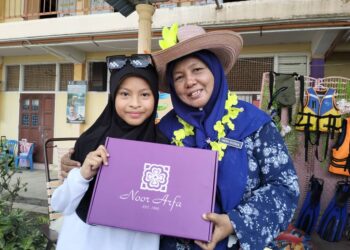 PUTERI Ayuni Balqis Muhammad Bahari menyampaikan hadiah baju kurung batik kepada gurunya, Nor Risah Aziz di SK Tengku Bariah, Kuala Terengganu, hari ini. - UTUSAN/KAMALIZA KAMARUDDIN