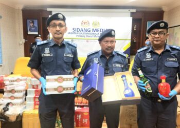 MOHD. ASRI Seman (tengah) menunjukkan antara minuman keras dan rokok yang dirampas dalam serbuan di Johor pada sidang akhbar di Bentong, Pahang.