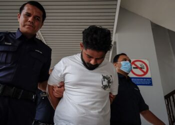 TERTUDUH diiring keluar anggota polis selepas mengaku tidak bersalah di Mahkamah Majistret, Ayer Keroh, Melaka atas pertuduhan memukul seorang pengawal keselamatan. - UTUSAN/SYAFEEQ AHMAD