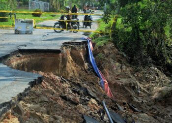 PENDUDUK melihat laluan utama keluar masuk di Kampung Batu 3, Mambau yang ditutup hari ini susulan kejadian tebing sungai runtuh.-UTUSAN/MOHD. SHAHJEHAN MAAMIN.