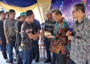 AMINUDDIN Harun menyampaikan bantuan kepada pengusaha kupang dan nelayan yang terjejas pada majlis di Pasir Panjang, Port Dickson hari ini.-UTUSAN/MOHD. SHAHJEHAN MAAMIN.