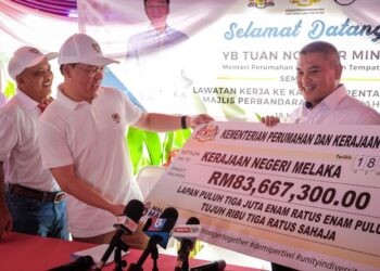 NGA Kor Ming menyerahkan replika cek kepada Pengerusi Kanan Jawatankuasa Perumahan, Kerajaan Tempatan, Saliran, Perubahan Iklim dan Pengurusan Bencana Melaka, Datuk Rais Yasin sempena program Sentuhan Kasih KPKT Ke-21 di Medan Selera Sultan Muhammad, Batu Berendam, Melaka. - UTUSAN/SYAFEEQ AHMAD