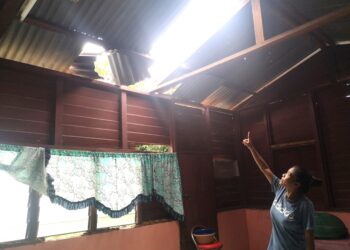 SEORANG penduduk Kampung Batang Benar, di Nilai, Seremban, Ruziana Zakaria menunjukkan bahagian zink bumbung rumahnya yang telah diterbangkan angin dalam kejadian yang berlaku kelmarin.-UTUSAN/NUR SHARIEZA ISMAIL.