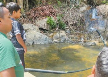 GHAZALI Abdullah bersama anak-anaknya melihat punca aliran air yang mula mengalir keluar di Jeram Pasu, Pasir Puteh, Kelantan. – UTUSAN/TOREK SULONG