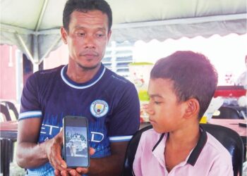 NOOR Azmi Ariffin menunjukkan gambar Allahyarham Faridah Abd Rahman kepada anaknya ketika ditemui di Kampung Sungai Mati, Tobiar di Pendang. – UTUSAN/JAMLIAH ABDULLAH