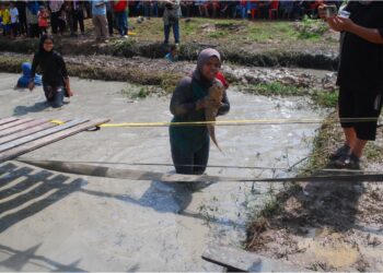 SYARAFIZA Zahari menunjukkan ikan keli yang berjaya ditangkapnya dalam pertandingan ‘ngoca’ ikan kategori wanita bersempena Jom Ngoca Raya Kuala Sungga, Tebong, Melaka. – UTUSAN/AMRAN MULUP