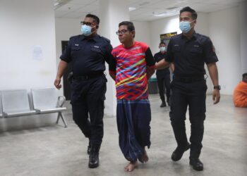 TERTUDUH diiringi anggota polis semasa dihadapkan di Mahkamah Sesyen, Kota Bharu, Kelantan hari ini-UTUSAN/ROSALWANI CHE SOH.