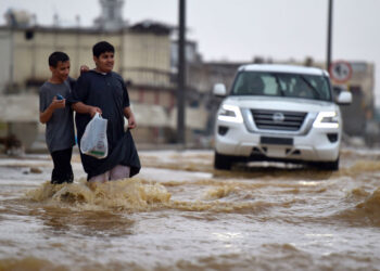 DUA remaja meredah banjir di bandar Jeddah pada 24 November 2022. -AFP