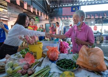 PANG Sock Tao menyapa dan menyerahkan bunga teluki kepada penduduk di Pasar Peladang, Kuala Kubu Baharu, Hulu Selangor, Selangor, semalam. – UTUSAN / M. FIRDAUS M. JOHARI