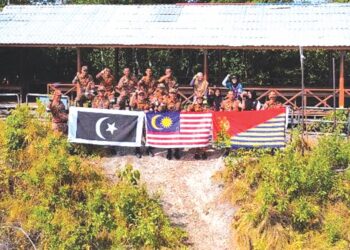 PEGAWAI dan anggota JBPM Terengganu mengibarkan  bendera di puncak Bukit Keluang, Besut, baru-baru ini.