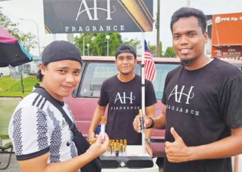 SYAZMIL Faizal Zainudin (kanan) dan Asyraf Hussain (tengah) menjual minyak wangi mampu milik di pasar malam atau pasar sehari di Kampar. – UTUSAN/MEGAT LUTFI MEGAT RAHIM