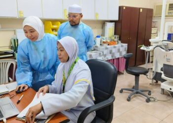 DR. UMAIRAH Razali (tengah) bersama petugas unit pergigian memeriksa data pesakit.