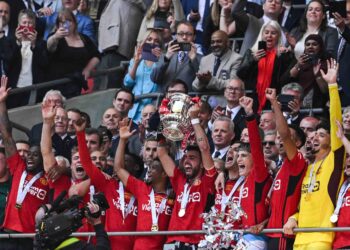 Kapten Manchester United, Bruno Fernandes menjulang trofi Piala FA sambil disaksikan rakan sepasukan selepas menewaskan Manchester City 2-1 dalam perlawanan akhir di Stadium Wembley, kelmarin. – AFP