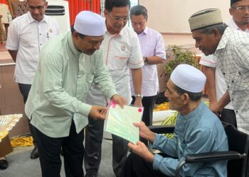 MOHD. Nassuruddin Daud (kiri) menyerahkan geran tanah kepada salah seorang peneroka di Felda Chiku 3, Gua Musang, Kelantan.-UTUSAN/AIMUNI TUAN LAH.