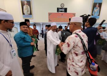 MOHD. Nassuruddin Daud (kiri) bersalam sambil mengucapkan selamat jalan kepada jemaah haji Kelantan yang berangkat ke Mekah di Kompleks Islam Jubli Perak Sultan Ismail Petra di Panji, Kota Bharu, Kelantan malam tadi. UTUSAN/MUSTAQIM MOHAMED.