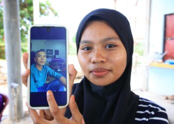SAIDATUL Nur Hanisa Saidi menunjukkan gambar ayahnya yang dikhuatiri hilang selepas terjatuh ke dalam Sungai Kelantan di Kampung Kutan Hulu, Wakaf Bharu, Kelantan-UTUSAN/KAMARUL BISMI KAMARUZAMAN