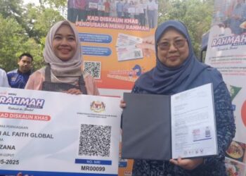 FUZIAH Salleh (kanan) menyerahkan Kad Diskaun Khas Menu Rahmah kepada peniaga gerai Nasi Ayam Berempah, Suzana Hanum di Nilai hari ini.