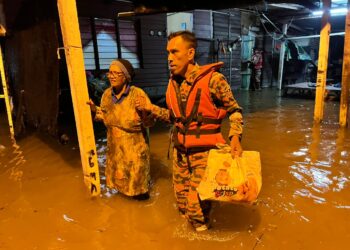 SEORANG penduduk meredah banjir di Kampung Batu 9, Jalan Changkat Jong di Teluk Intan semalam. - UTUSAN/AIN SAFRE BIDIN