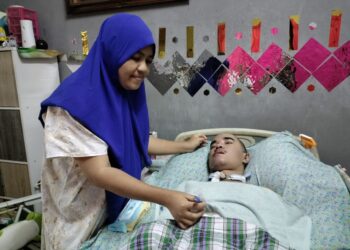 SHAPIDAH Shahid membetulkan tiub makanan anaknya, Mohd. Zaki Hanapi yang koma di kediamannya di Taman Kaseh, Kluang.