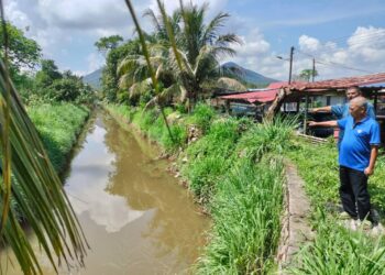 MUHAMMAD Rahman (kanan) dan Azman menunjukkan tali air berhampiran Taman Ilham yang perlu didalamkan bagi mengatasi limpahan air sehingga menyebabkan banjir kilat di taman perumahan berkenaan.