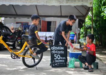 MUHAMMAD Irfan Syed Taib (kanan) menjual aiskrim Malaysia di hadapan rumahnya di Kampung Paya Datu, Manir, Kuala Terengganu, kelmarin. – UTUSAN/PUQTRA HAIRRY ROSLI