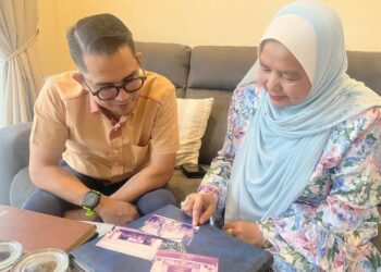 UMMI Mariza Che Ya  bersama Mohd. Azmawi Fikri Abdul Ghani melihat gambar kenangan mereka ketika di bangku persekolahan. 
– utusan/AIMUNI TUAN LAH