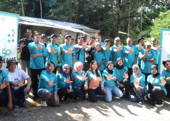 Sukarelawan PETRONAS menunjukkan tanda lima  sempena PETRONAS 50 Dreams di Kampung Pulau Tanjung Surat, Kota Tinggi. 
– UTUSAN/RAJA JAAFAR ALI