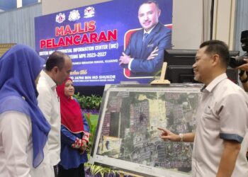 AZLIKAMIL Napiah (kanan) menerangkan penggunaan sistem GIC yang dibangunkan pihaknya dan MPK kepada Mohd. Jafni Md. Shukor di Dewan Tunku Ibrahim Ismail, Kluang.