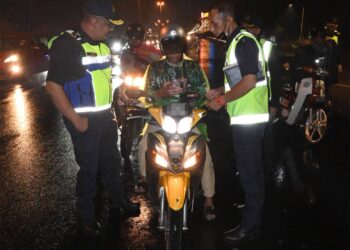 MUHAMMAD FIRDAUS Shariff melihat anggota penguat kuasa memeriksa seorang penunggang motosikal pada Op HRAA di Lebuh AMJ dekat Bukit Piatu, Melaka. - UTUSAN/AMRAN MULUP