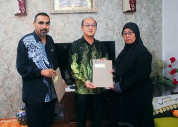 NGWE Hee Sam dan Nur Mohammad Bakhtir Mohamad Akhir menyampaikan pencen penakat kepada Purina Samsuri di Rumah Awam 1, Pulau Gadong, Melaka. - UTUSAN/AMRAN MULUP