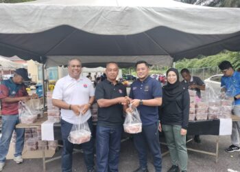 MOHD. FA'IZ Salehon (dua dari kanan) dan Zakaria Dullah menyampaikan daging korban kepada salah seorang penerima di Kompleks MDSR, Simpang Renggam.