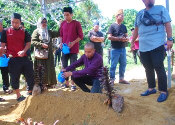 MUHAMMAD HANIS Kamaruldzaman menyiram kubur Allahyarham Kamal Bakar di Tanah Perkuburan Islam Bukit Baru Dalam, Melaka. - UTUSAN/AMRAN MULUP