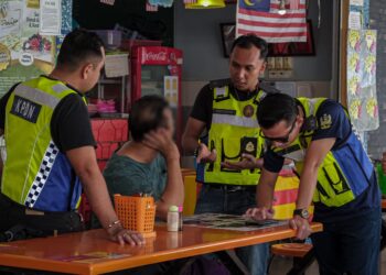 PENGUAT kuasa KPDN bertanyakan sesuatu kepada peniaga terlibat di Medan Selera Jalan Tun Ali, Kampung Morten, Melaka. - UTUSAN/SYAFEEQ AHMAD